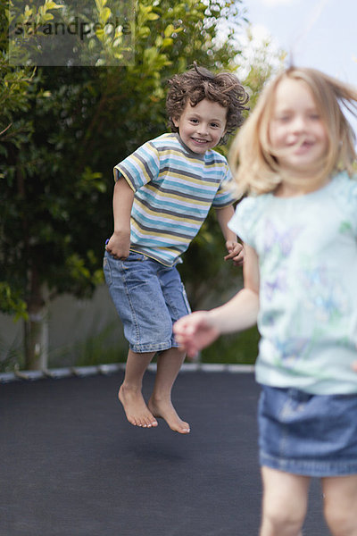 Lächelnde Kinder springen auf Trampolin