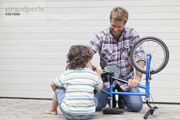 Vater hilft Sohn Fahrrad reparieren