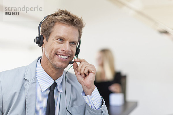 Geschäftsmann mit Headset am Schreibtisch