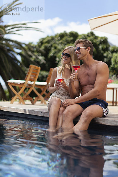 Couple toasting each other by pool