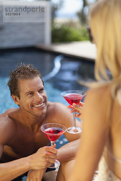 Couple toasting each other in pool