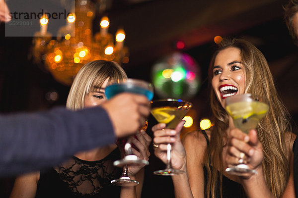 Lächelnde Frauen beim Cocktail im Club