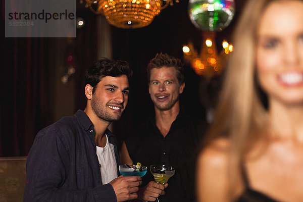 Lächelnde Männer beim Cocktail im Club