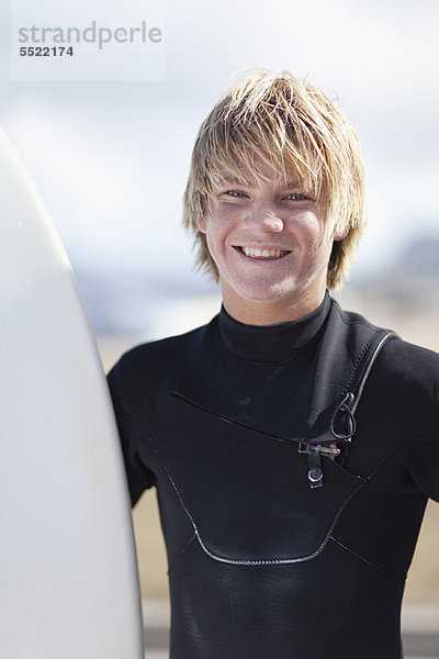 Teenager-Surfer mit Haltebrett am Strand