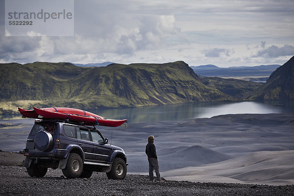 Mann mit Jeep bewundert ländliche Landschaft