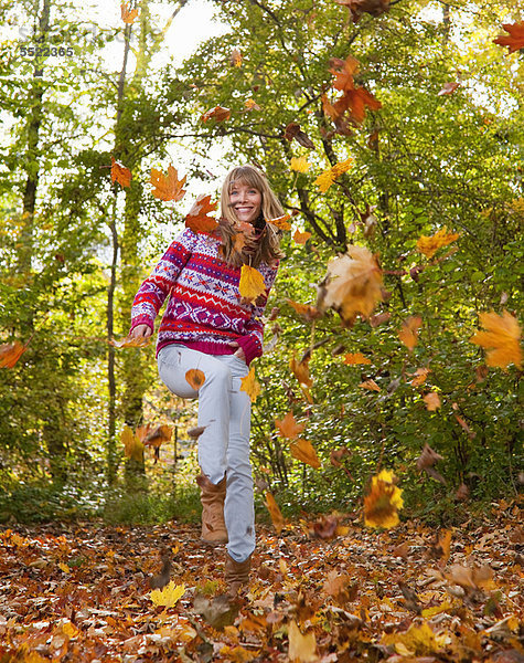 Frau spielt im Herbstlaub