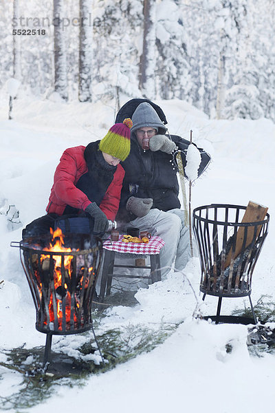 Paar Picknick bei Feuer im Schnee