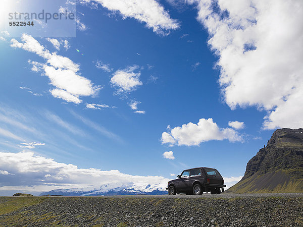 Auf Kies geparkter Jeep in ländlicher Landschaft