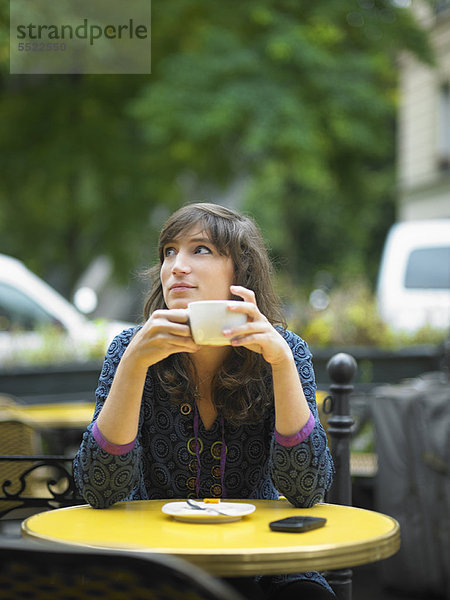 Frau beim Kaffeetrinken im Straßencafé