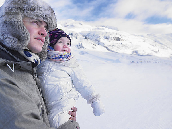 Vater hält Baby in verschneiter Landschaft