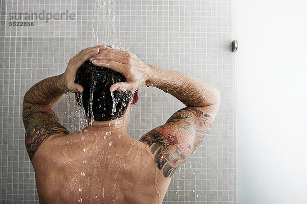 Mann wäscht sich die Haare unter der Dusche