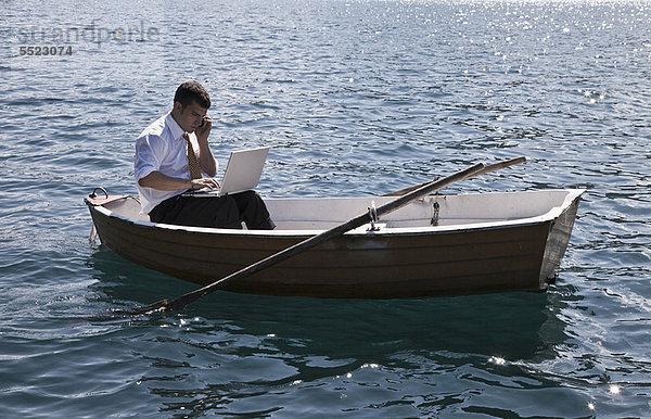 Geschäftsmann  der im Ruderboot arbeitet.