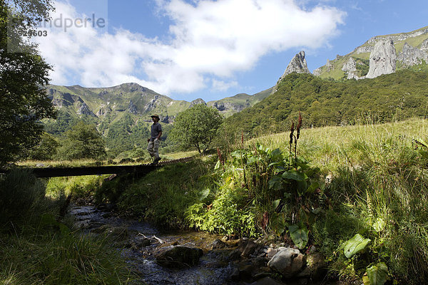 Wanderer überqueren eine Fußbrücke  Chaudefour-Tal  Naturschutzgebiet  Parc Naturel Regional des Volcans d'Auvergne  Regionaler Naturpark der Vulkane der Auvergne  Puy de Dome  Frankreich  Europa