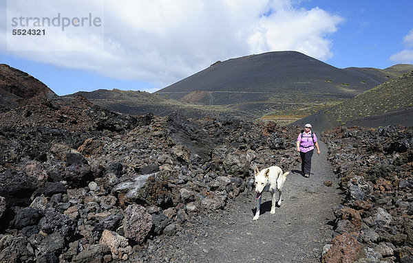 Frau mit Hund beim Wandern auf La Palma  hinten Vulkan San Antonio  Kanaren  Kanarische Inseln  Spanien  Europa  ÖffentlicherGrund