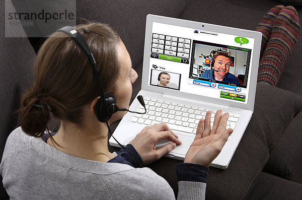Junge Frau sitzt am Laptop und telefoniert über das Internet  per Webcam wird das Livebild beider Teilnehmer übertragen