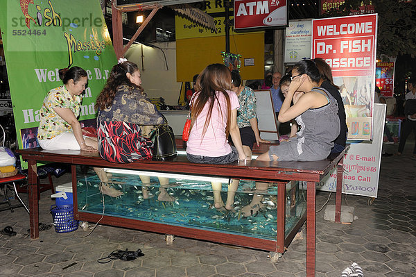 Khmer Frauen lassen sich am Straßenrand von Doktor-Fischen eine Fischmassage an ihren Füßen geben  Siem Reap  Kambodscha  Südostasien  Asia