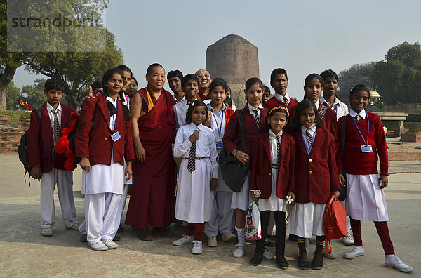 Indische Mädchen einer Schulklasse beim gemeinsamen Foto mit buddhistischen tibetischen Mönchen und Rinpoche vor der Dhamekh Stupa  Wildpark von Isipatana  Sarnath  Uttar Pradesh  Indien  Südasien  Asien
