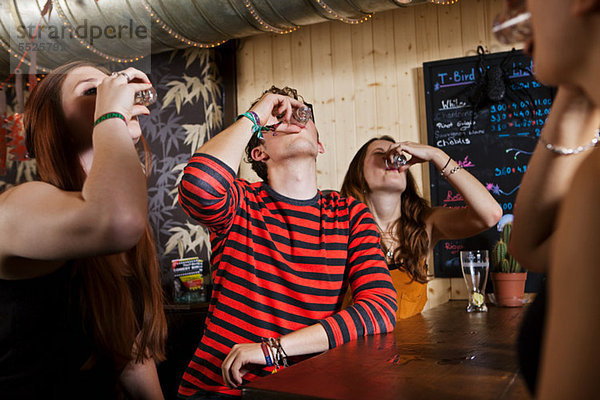 Junge Freunde trinken aus Schnapsglas in der Bar