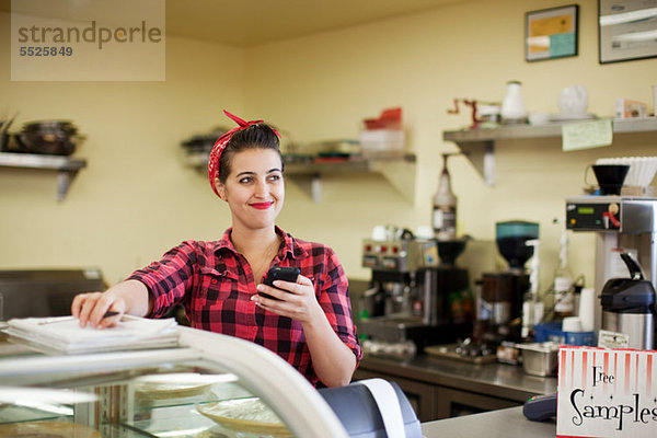 Young Woman holding Cellphone in Bäckerei