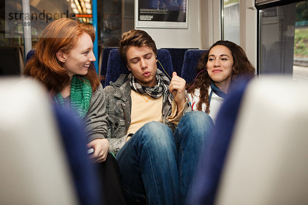 Drei junge Freunde  die im Zug unterwegs sind und Musik hören.