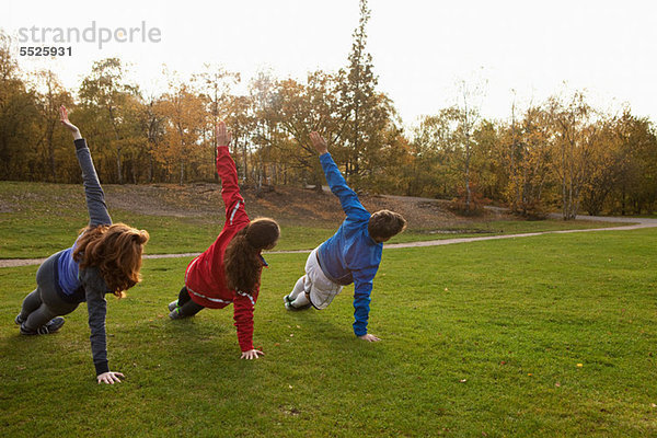 Drei junge Freunde  die sich auf Gras im Park ausstrecken.