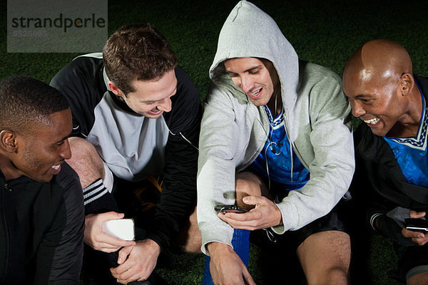 Fußballspieler beim Blick auf das Handy auf dem Spielfeld