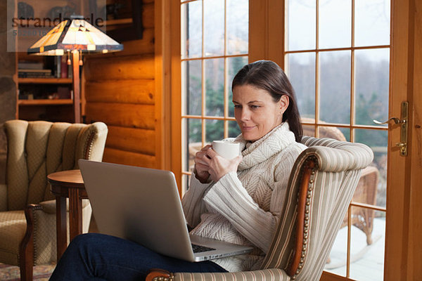 Reife Frau entspannt im Sessel mit Laptop