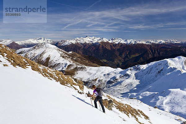 Wanderin beim Aufstieg im Schnee zur Röthenspitz oberhalb vom Penser Joch  hinten das Gebirge des Pfitschertals mit dem Hochfeiler  Sarntal  Südtirol  Italien  Europa