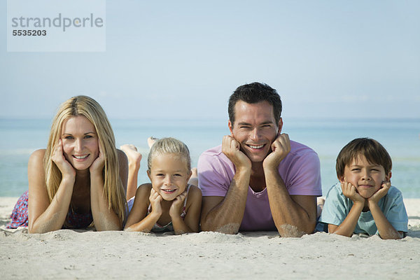 Familie auf Sand am Strand liegend  Portrait