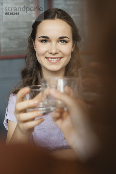 Junge Frau  die mit einem Freund Glas erhebt