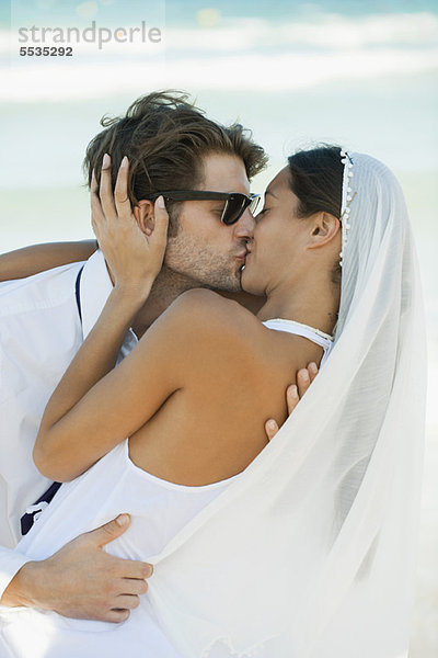 Brautpaar beim Küssen am Strand