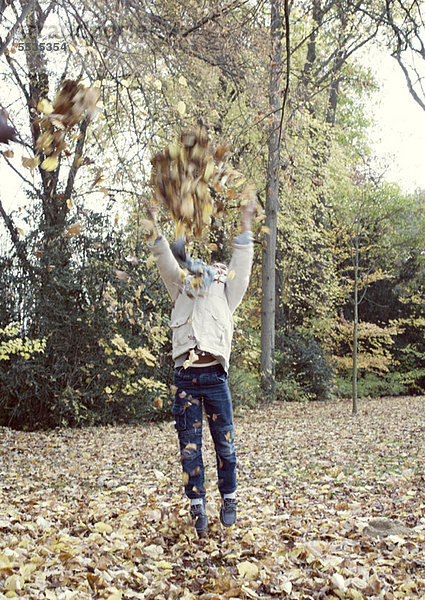 Junge springt zu Baumästen mit Herbstblättern  verschwommene Bewegung
