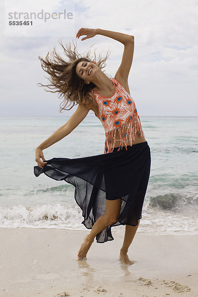 Frau beim Tanzen und Haare werfen am Strand
