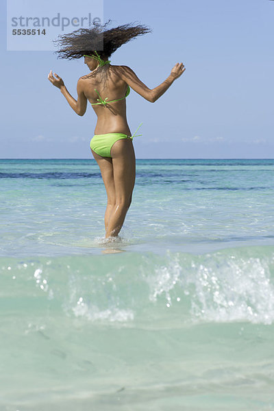 Frau im Bikini im Wasser stehend  Kopf schüttelnd