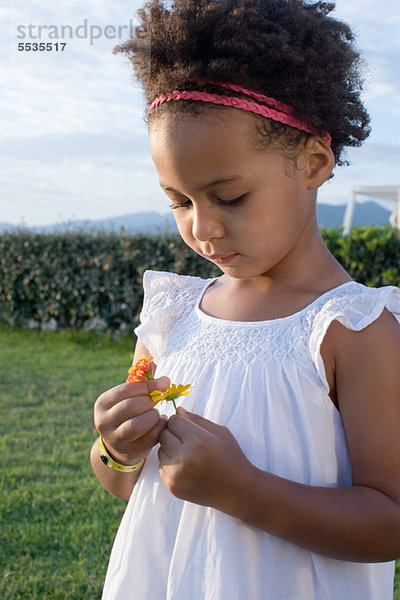 Kleines Mädchen schaut sich Blumen an