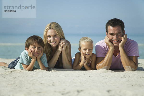 Familie auf Sand am Strand liegend  Portrait