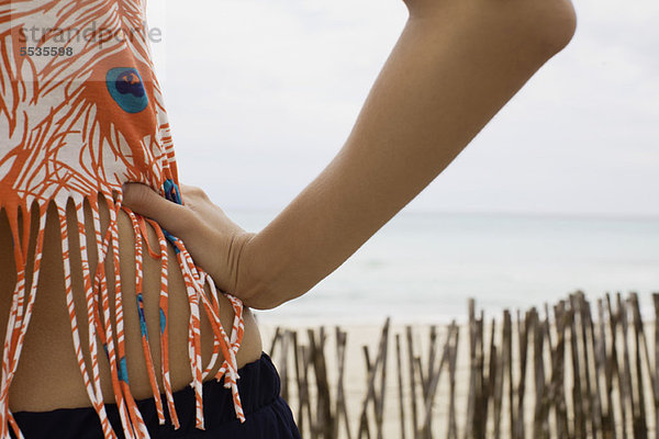 Frauenhand auf Hüfte  Strand im Hintergrund