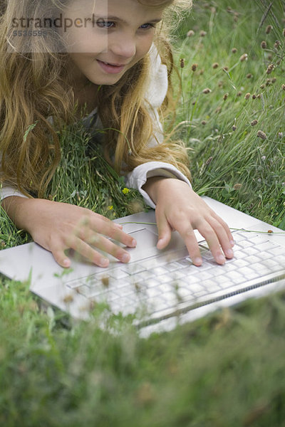Mädchen im Gras liegend  mit Laptop-Computer