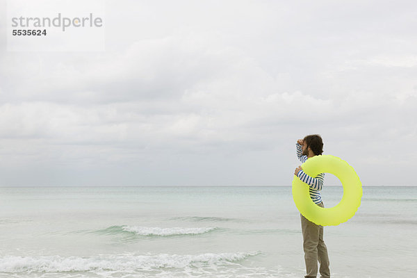 Junger Mann mit Schwimmring  Blick in die Ferne