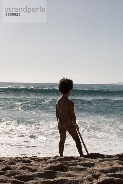 Kleines Mädchen steht nackt am Strand  Rückansicht