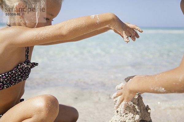 Mädchen spielt im Sand am Strand