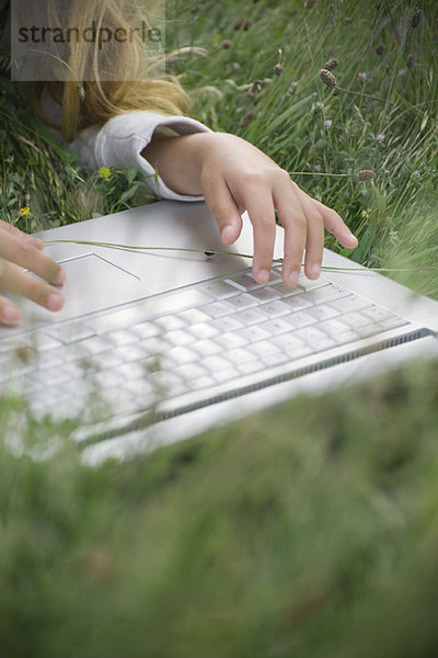 Mädchen im Gras liegend  mit Laptop-Computer