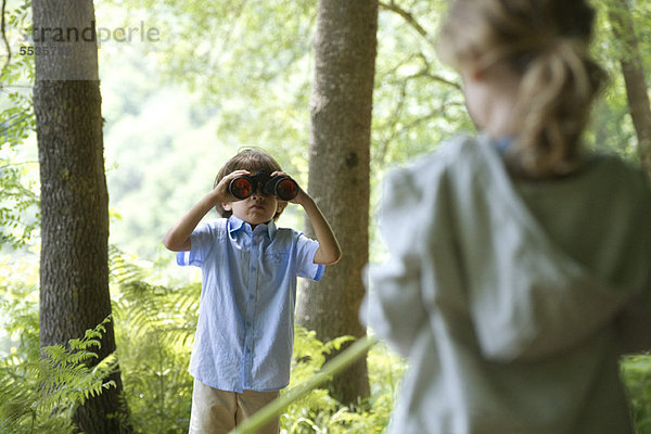 Kinder im Wald  Junge durchs Fernglas schauend