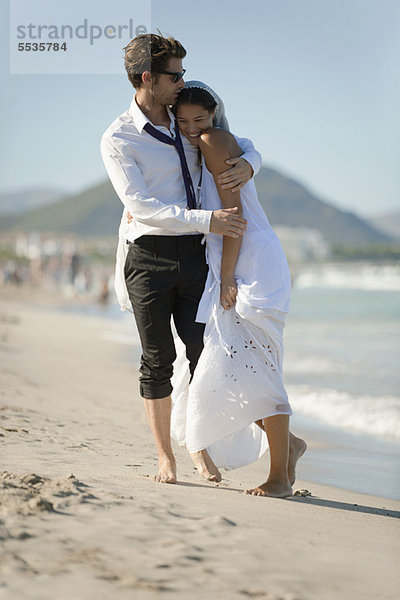 Braut und Bräutigam umarmend am Strand