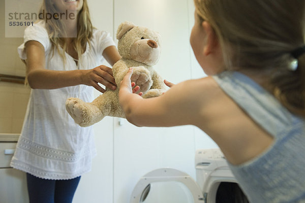 Kleines Mädchen erhält frisch geputztes Teddybärchen von Mutter