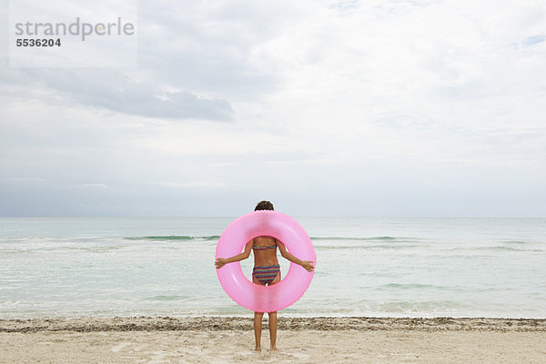 Mädchen mit aufblasbarem Ring am Strand  Rückansicht