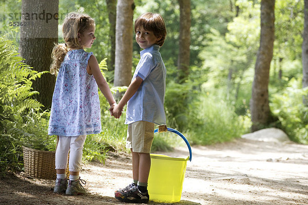 Kinder halten sich auf einem Waldweg an den Händen
