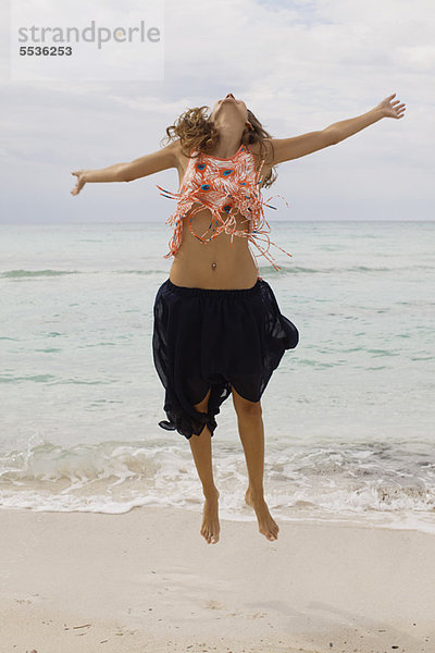 Frau beim Springen in der Luft am Strand