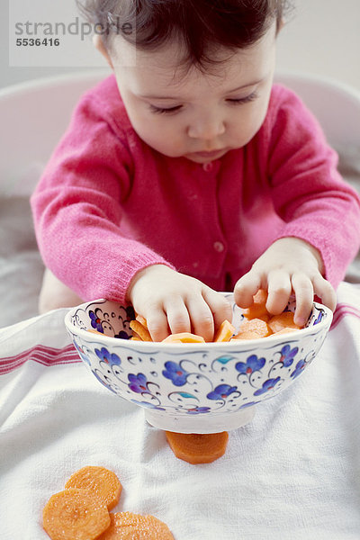 Kleinkind spielt mit Karottenschale