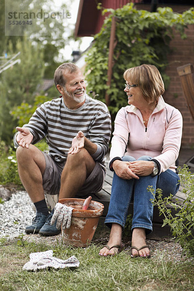 Aktives Seniorenpaar spricht im Garten über Gartenarbeit